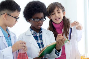 Group of multiracial children wearing lab coats read carefully the text of a book to check the...