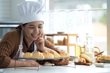 Happy homemade bakery chef, woman wearing a chef's hat and apron looks proudly at the bread fresh...