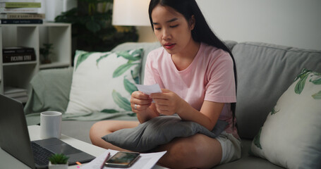 Portrait of Young Asian woman holding paper various expense bills and plans for personal finances...