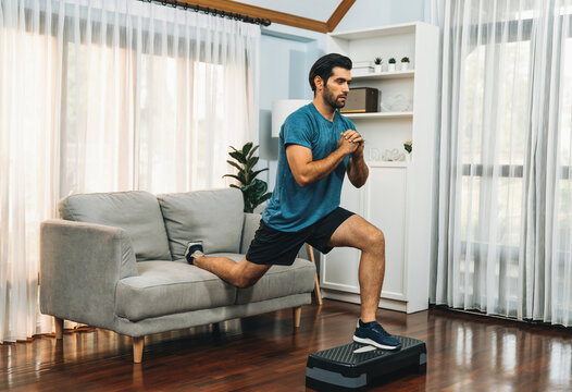Athletic and sporty man doing squat during home body workout exercise session for fit physique and healthy sport lifestyle at home. Gaiety home exercise workout training concept.