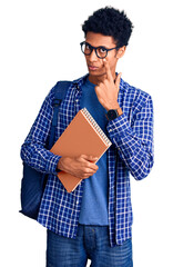Young african american man wearing student backpack holding book pointing to the eye watching you gesture, suspicious expression