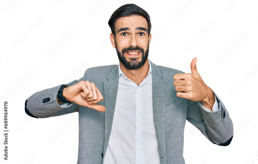 Wall mural Young hispanic man wearing business clothes doing thumbs up and down, disagreement and agreement expression. crazy conflict