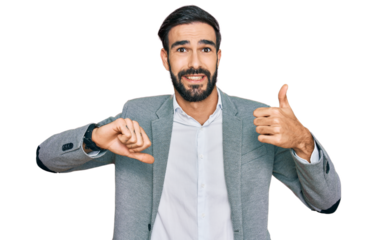 Young hispanic man wearing business clothes doing thumbs up and down, disagreement and agreement expression. crazy conflict
