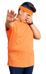 Little boy kid wearing sportswear covering eyes with hands and doing stop gesture with sad and fear expression. embarrassed and negative concept.