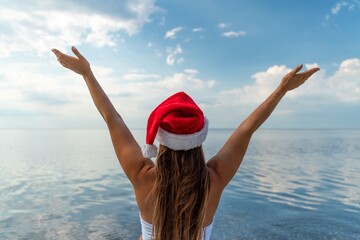 Woman traveller arms raised santa. Happy relaxed woman in the santa hat breathing fresh air raising...