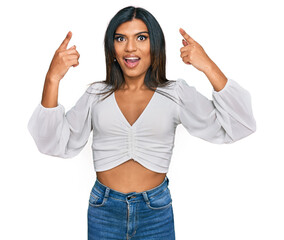 Young latin transsexual transgender woman wearing casual clothes smiling amazed and surprised and pointing up with fingers and raised arms.
