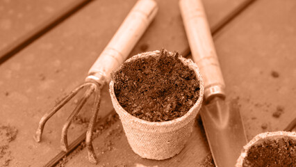 Eco friendly biodegradable peat pots and garden tools. Image toned in Peach Fuzz color of the year...