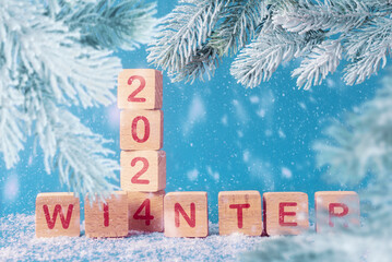 Wooden blocks with inscription 2024 winter and frosty Christmas tree branches. Blue snowy...