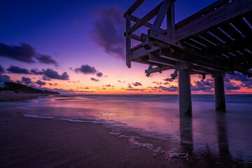Sunset over wooden pier on the sea beach - obrazy, fototapety, plakaty