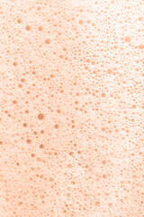 The texture of soap foam with bubbles on a Peach Fuzz background.