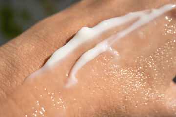 Fototapeta premium A smear of white moisturizer or sunscreen on a woman's hand.