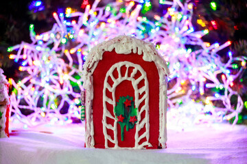 A gingerbread house decorated with colorful garlands and a Christmas tree.