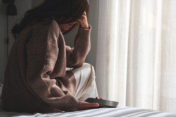 A sad woman after reading bad news on smartphone in bedroom - obrazy, fototapety, plakaty