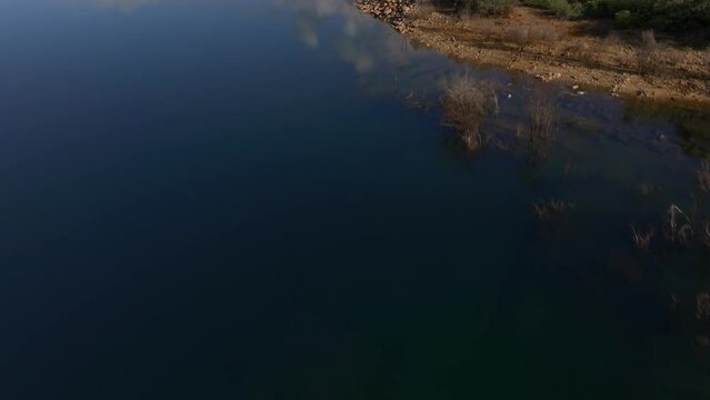 Push forward and tilt up of Serpentine Dam, Western Australia. Smooth water with reflections, native bush.