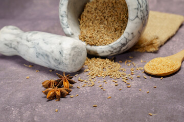 Whole dried anise seeds (Pimpinella anisum) in a ceramic mortar and pestle, with ground anise and...