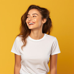 Fototapeta premium A girl on a yellow background in a white T-shirt stands and smiles