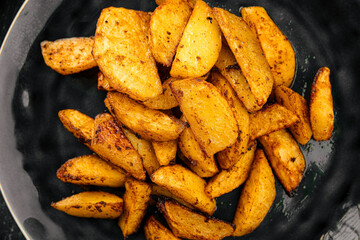 Portion of baked potato wedges on grey background