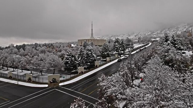 Drone flies above snowy trees and road to establish Provo LDS Mormon Temple