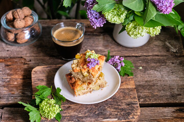 Blondie with white chocolate and walnuts. Side view, wooden background, rustic, lilac flowers.
