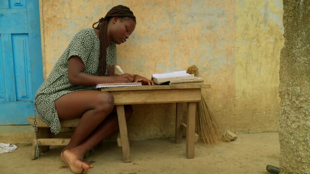 Reading and writing, a local girl is trying to gain some basic education to help bridge the gender gap in the village of Kumasi in Ghana, Africa.