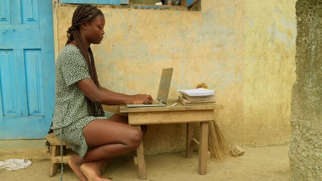 Browsing the internet while studying online, the young woman is getting access to education from her village in Kumasi, Ghana, in Africa.