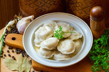 Traditional dumplings on a plate. Dumplings with spices and herbs on a wooden background. Fresh dumplings close-up.