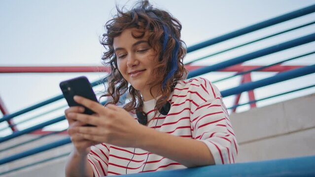 Smiling teenager reading smartphone message on street close up. Girl messaging 