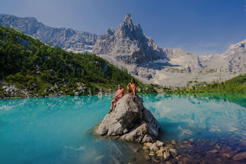 A couple of men and women visit Lago di Sorapis in the Italian Dolomites, milky blue lake Lago di...