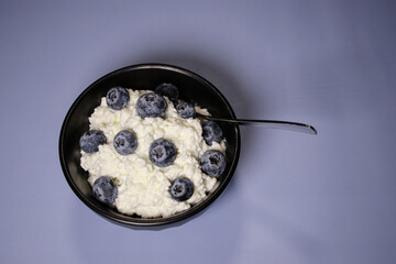 Close up of cottage cheese with fresh blueberries in black bowl, hight protein dessert