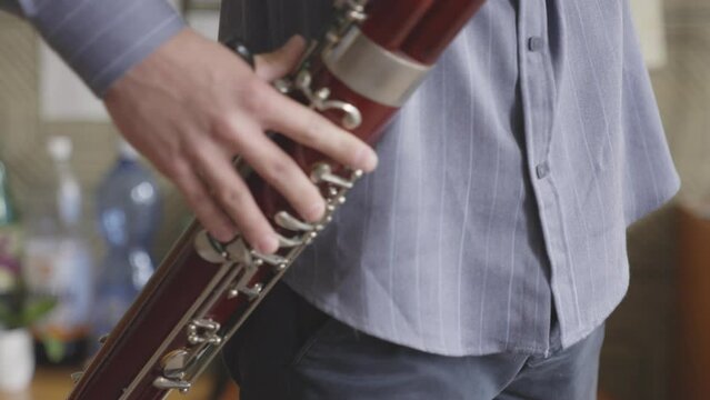 Young male student practice to play Bassoon in Music School. - close up