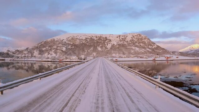 Journey through the frosty vistas of Lofoten, Norway, on a winter road, where snow-covered surroundings paint a stunning picture.