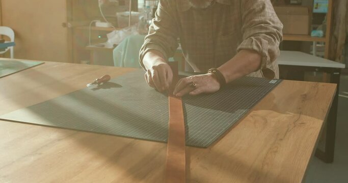 old talented craftsman smoothing edges of leather, sewing belts for sale Mature Artisan uses Leather edger at workplace. Male Cleaning Up the Edges of the Leather Belt. slow motion