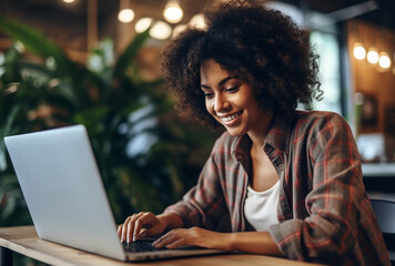 Fototapeta premium Attractive young black woman sitting in front of a laptop smiling