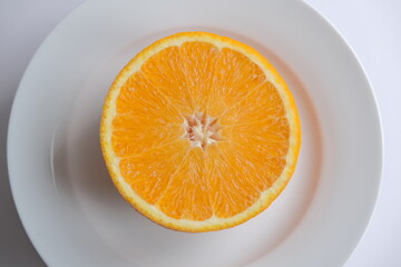 ripe and juicy orange. fresh orange cut in half on a white plate