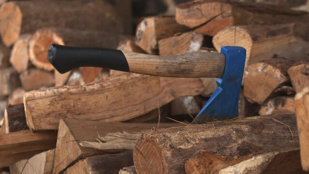 Person sticking work axe into a cut and stacked piece of log. Close up