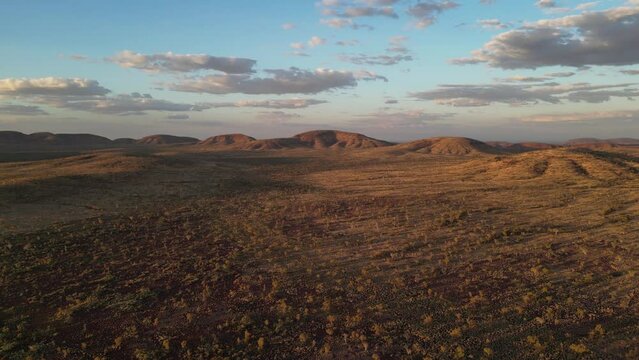 Beautiful landscape of Australian desert with rocky mounts in background at sunset, Karijini Area in Western Australia. Aerial panning