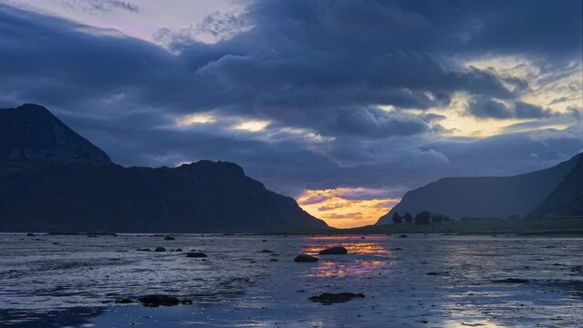 The sea water's recapturing of the lowlands during the tide; the clouds move from the foreground towards the horizon behind the mountains where the sea rests in the sunset. Lofoten, Northern Norway.