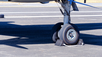 Close-up of front wheels of airplane with chock, Airplane parked at the airport, aircraft...