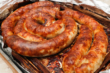 Spiral grilled homemade sausage. Baked homemade sausage close up. Delicious Bavarian sausages.