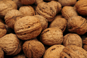 Walnuts in a shell. Background with many walnuts. Ripe walnut sold in the market