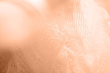 Texture of a colored nylon washcloth close-up. Color peach fuzz
