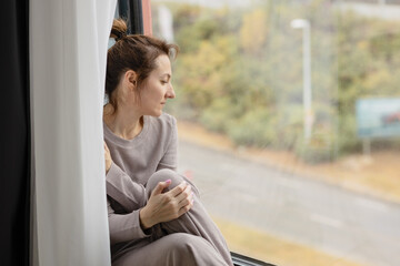 Portrait of woman in casual clothes looking through the window