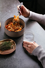 the girl is eating buckwheat noodles with vegetables, sauce and shrimp