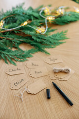 Festive handwritten gift tags with holiday greenery on wooden surface