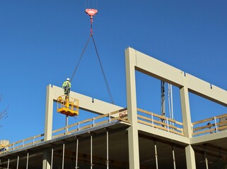 Worker on a scissor lift during the installation of new building pillars in the construction site