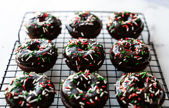 High angle close up of chocolate donuts with Christmas sprinkles.