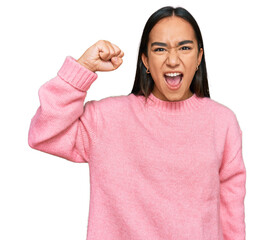 Young asian woman wearing casual winter sweater angry and mad raising fist frustrated and furious while shouting with anger. rage and aggressive concept.