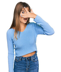 Teenager caucasian girl wearing casual clothes peeking in shock covering face and eyes with hand, looking through fingers with embarrassed expression.