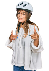 Teenager caucasian girl wearing bike helmet pointing fingers to camera with happy and funny face. good energy and vibes.