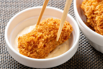 カキフライにタルタルソースをつけて食べる。
